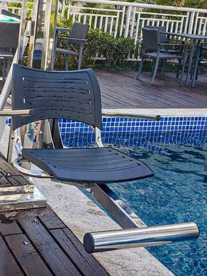 Cadeira recolhida na borda de uma piscina com deck de madeira