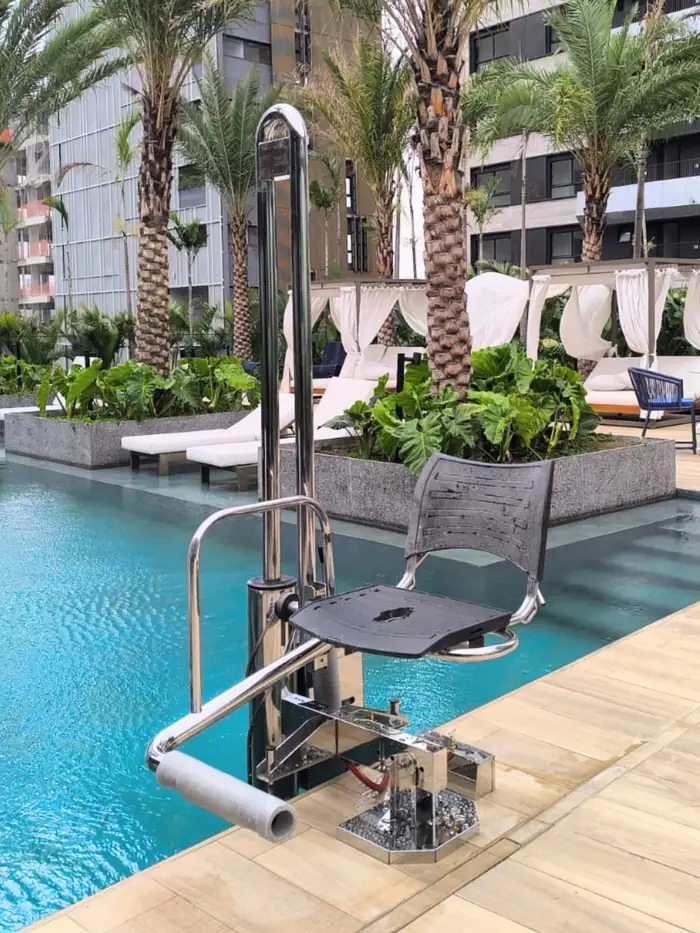 Elevador para piscina instalado em condomínio, com deck e palmeiras