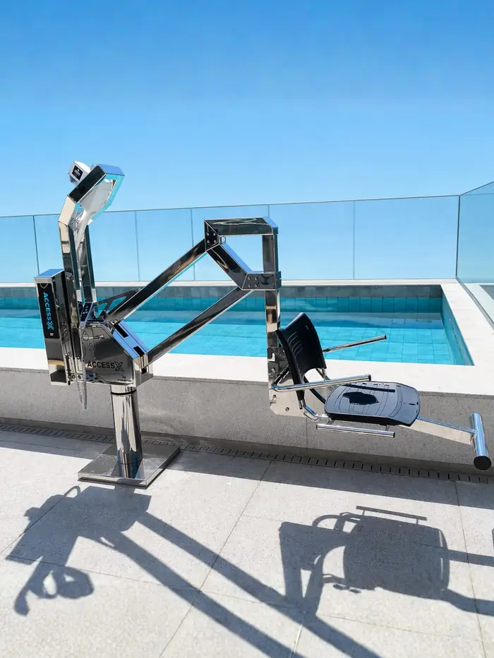 Equipamento de acessibilidade em piscina de cobertura com guarda-corpo de vidro